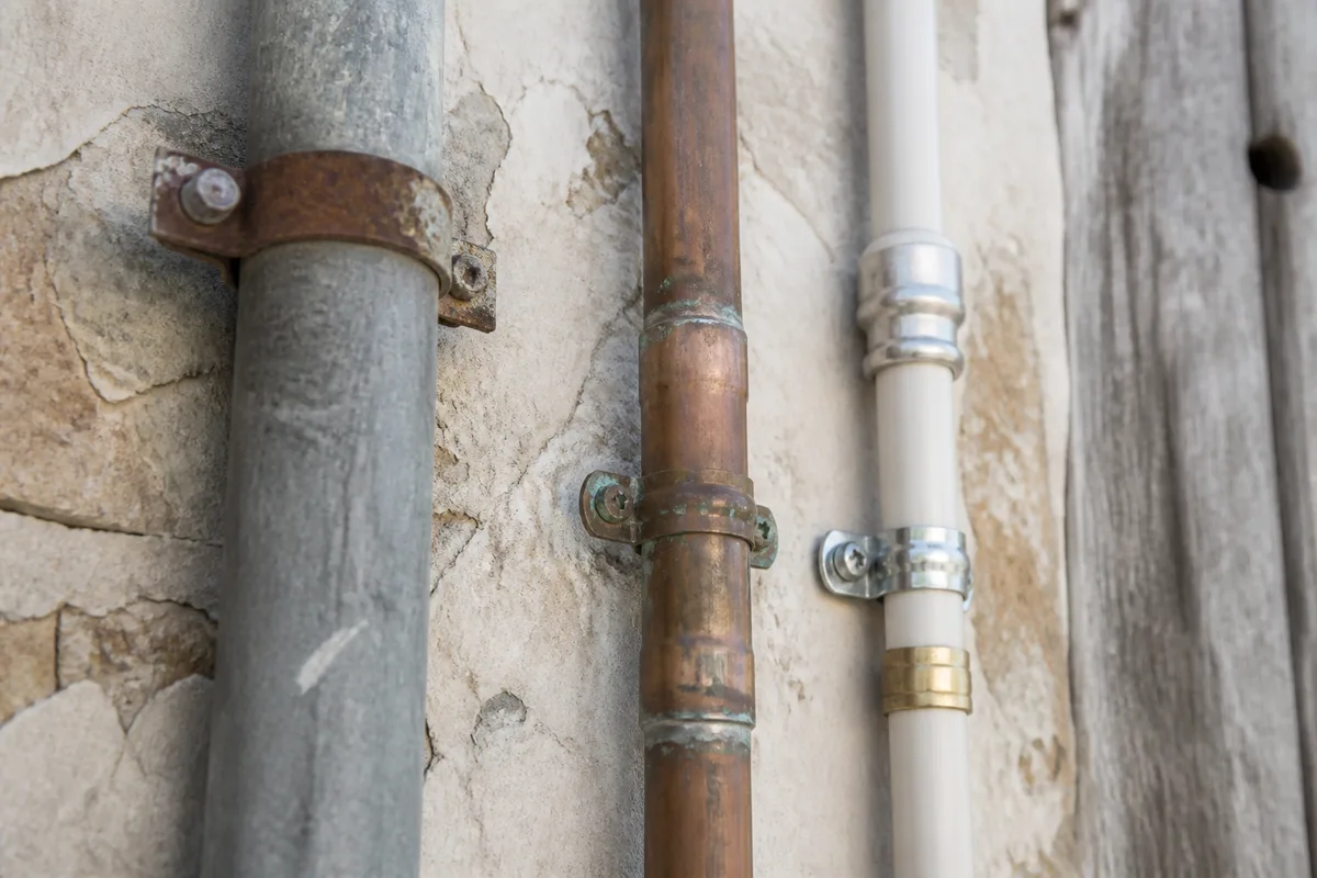 Canalisations en cuivre et raccords multicouche apparents le long d’un mur clair dans une maison ancienne de La Teste-de-Buch